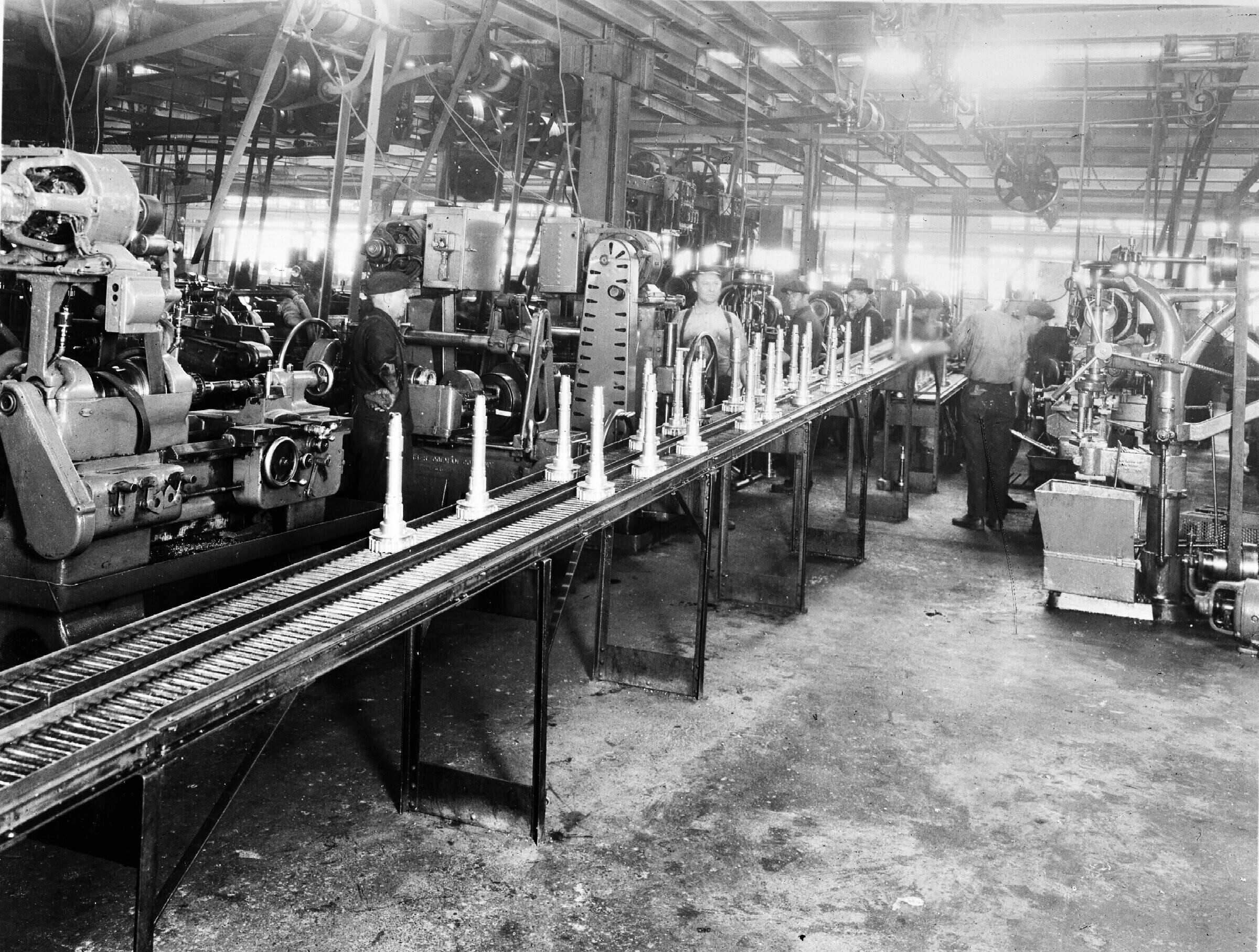 A car plant in 1924, with parts carried past the machines on a conveyor